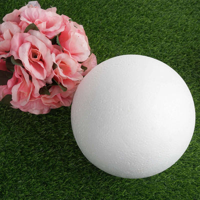 White foam ball on artificial grass with pink flowers.