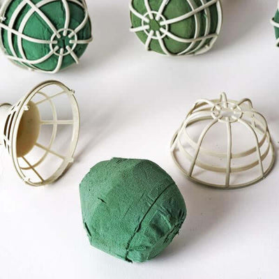 Green floral foam ball with plastic holder on white background