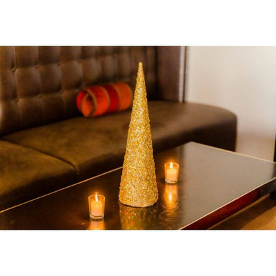 Gold glitter Christmas tree decoration with candles on a coffee table.
