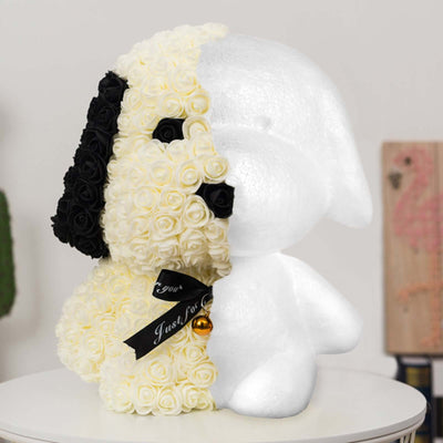 Dog-shaped floral arrangement in white and black roses on a table.