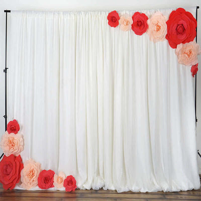 Floral backdrop with red and peach paper flowers on white drapery.