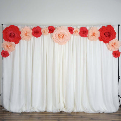 Large paper flowers on a white backdrop for event decoration.