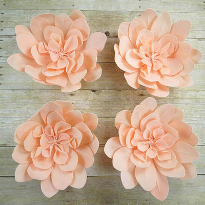 Peach paper flowers arranged in a square layout on a wooden background.