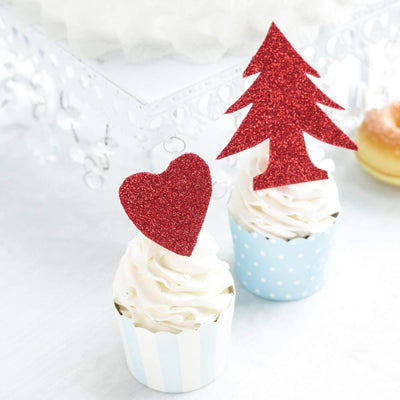 Cupcakes with red glitter heart and tree toppers on a white backdrop.