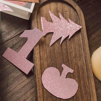 Pink glitter number and tree cutouts on a wooden tray.