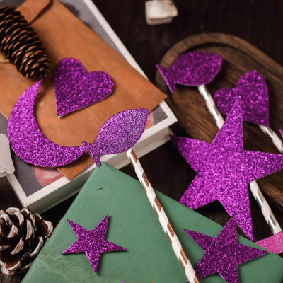 Purple glitter party decorations in various shapes on a wooden surface.