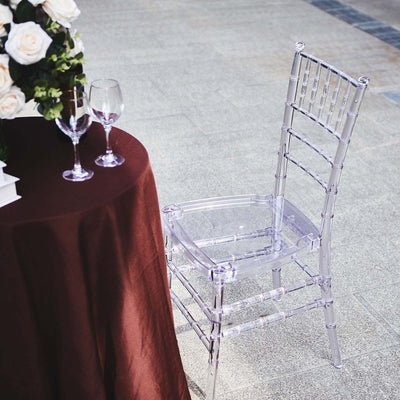 Clear acrylic chair beside a table with flowers and glasses.