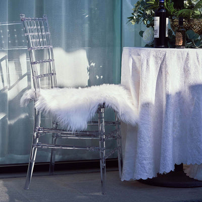Clear acrylic chair with a faux fur cushion beside a table.