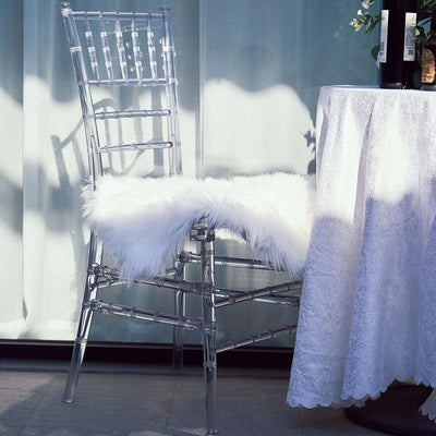 Clear acrylic chair with faux fur seat next to a table.