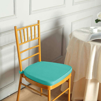 Turquoise cushion on a wooden chair beside a table with a cup.