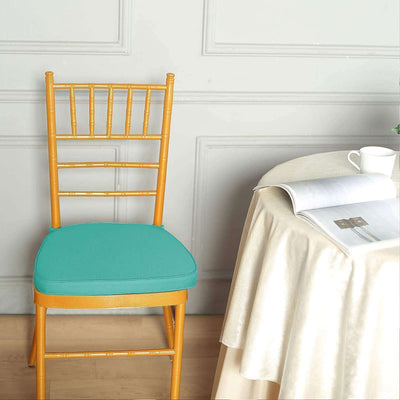 Gold bamboo chair with turquoise cushion next to a table and magazine.