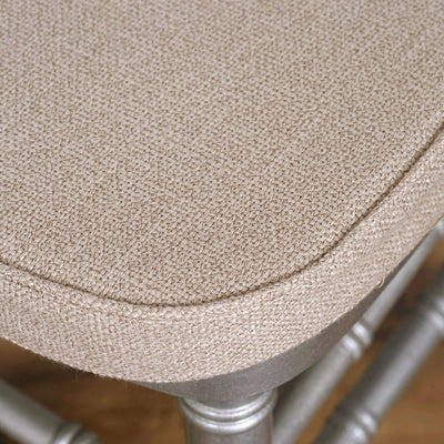 Close-up of a textured beige chair cushion with silver legs.