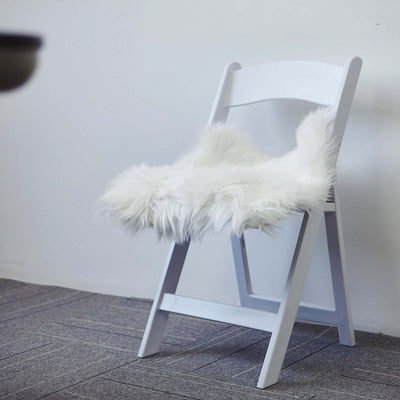 White folding chair with a fluffy white seat cover.