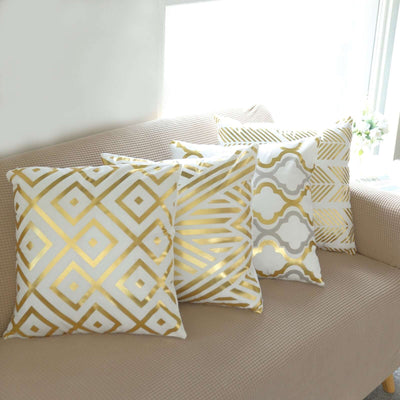 Decorative gold and white patterned throw pillows on a beige sofa.