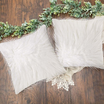 White faux fur throw pillows on a wooden surface.