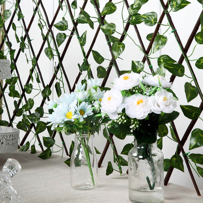 Artificial flower arrangements in glass vases on a decorative backdrop.
