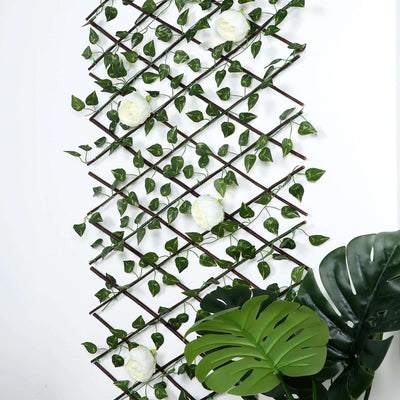 Artificial green vine trellis with white flowers and large tropical leaves.