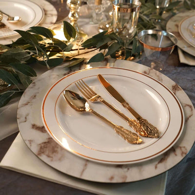Elegant marble plate setting with gold cutlery and greenery accents.