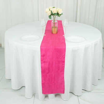 Pink table runner on a white table with floral centerpiece and glassware.
