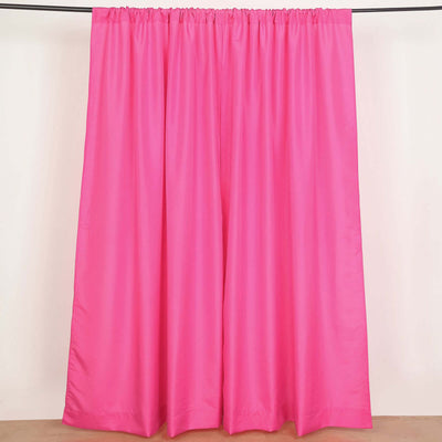 Pink curtains hanging on a rod in a studio setting.
