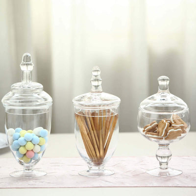 Three elegant glass jars filled with colorful candies, pretzel sticks, and cookies.