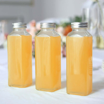 Three glass bottles filled with yellow juice on a table.