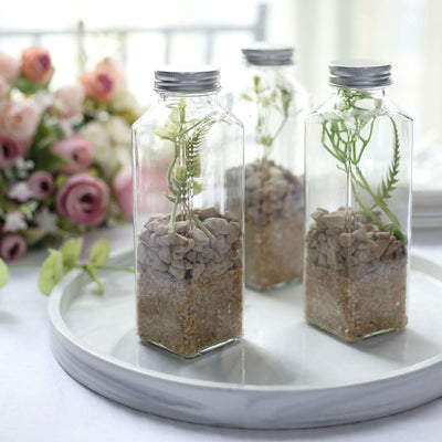 Glass terrarium bottles with pebbles and plants on a tray