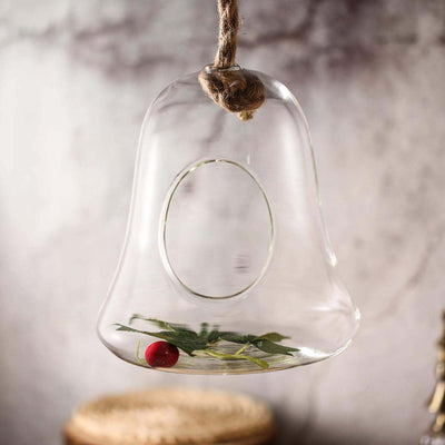 Glass bell jar with a cherry and leaves inside, hanging from a twine loop.