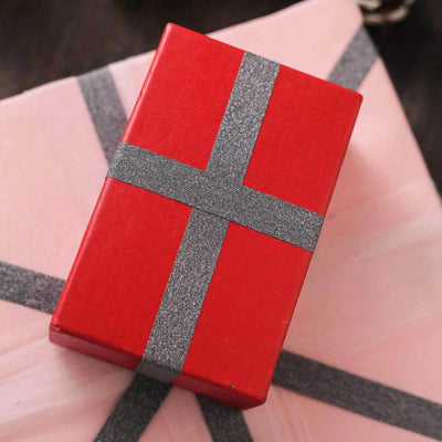 Red gift box with silver ribbon on a pink background.