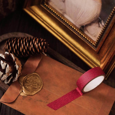 Red glitter washi tape on a rustic background with a letter and decorative elements.