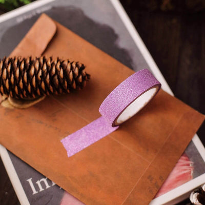 Purple glitter washi tape on a brown envelope with a pinecone.