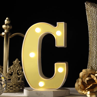 Marquee letter light 'C' with illuminated bulbs on a decorative table setting.