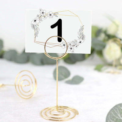 Gold table number holder with floral design card, perfect for events.