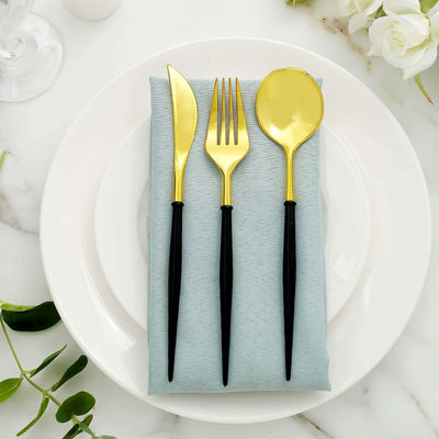 Gold cutlery set on a blue napkin atop a white plate.