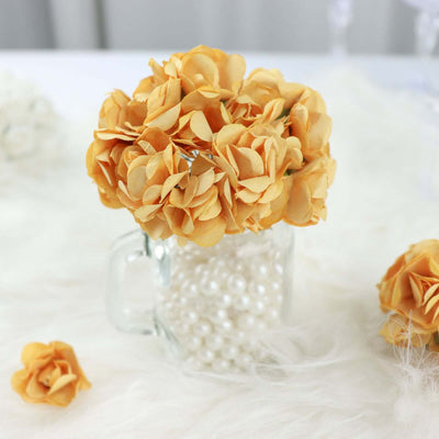 Yellow paper flower bouquet in a glass mug filled with pearls.