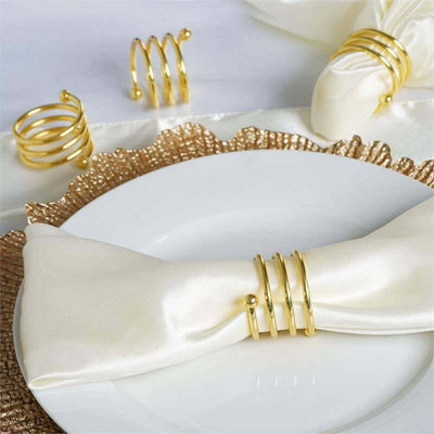 Gold napkin rings on a white plate with a satin napkin.