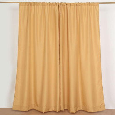 Gold curtain panels hanging on a rod against a plain backdrop.