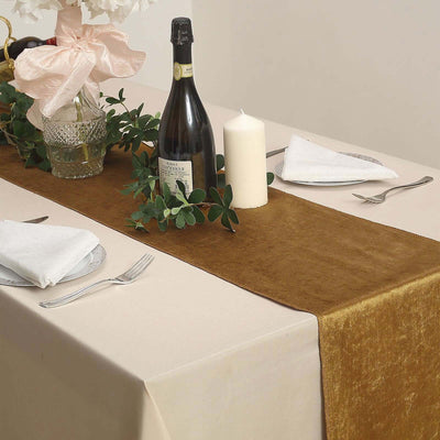 Elegant table setting with a gold runner, wine, candle, and floral decor.