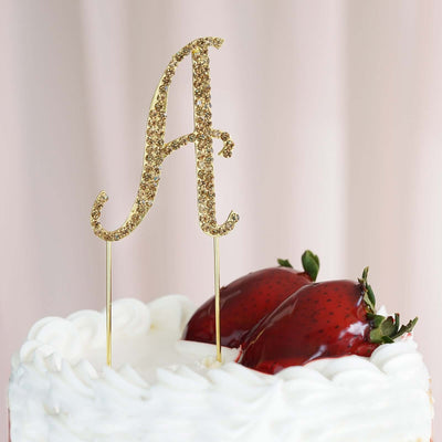 Gold glitter cake topper letter "A" on a decorated cake with strawberries.