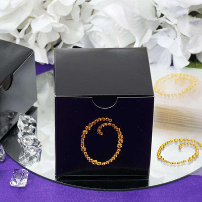 Black gift box with decorative amber rhinestone swirl design.
