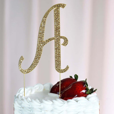 Gold glitter letter A cake topper with strawberries on a white frosted cake.