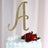 Gold glitter letter A cake topper with strawberries on a white frosted cake.