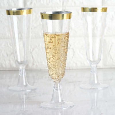 Clear champagne flutes with gold rims filled with bubbly drink.