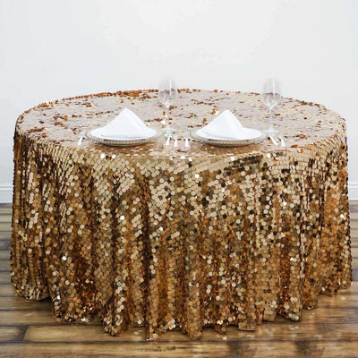 Gold sequin tablecloth on round table set for dining with plates and glasses.