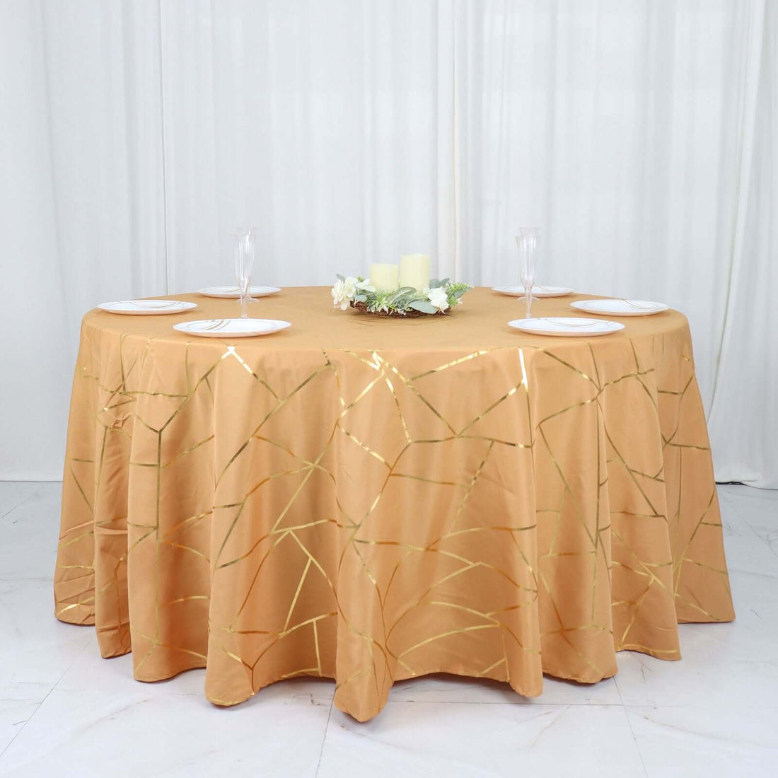 Round gold tablecloth with geometric design on a dining table setting.