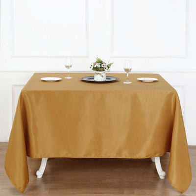 Elegant gold tablecloth draped over a dining table with plates and glasses.