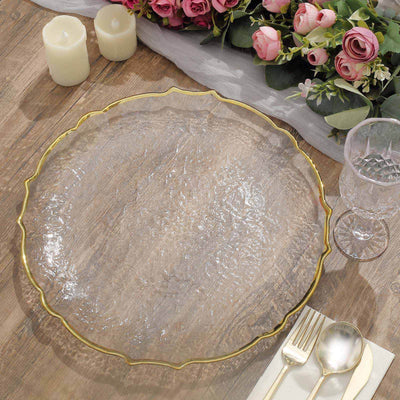 Elegant clear glass charger plate with gold trim on a wooden table setting.