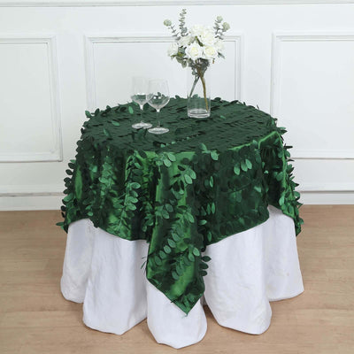 Green leaf tablecloth on a white table with glasses and flowers.