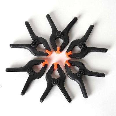 Black spring clamps arranged in a circular pattern with orange tips.