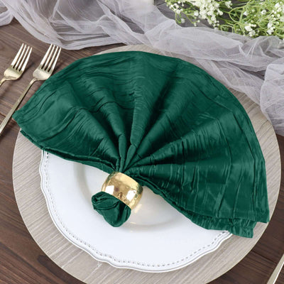 Green satin napkin elegantly arranged on a white plate with a gold napkin ring.